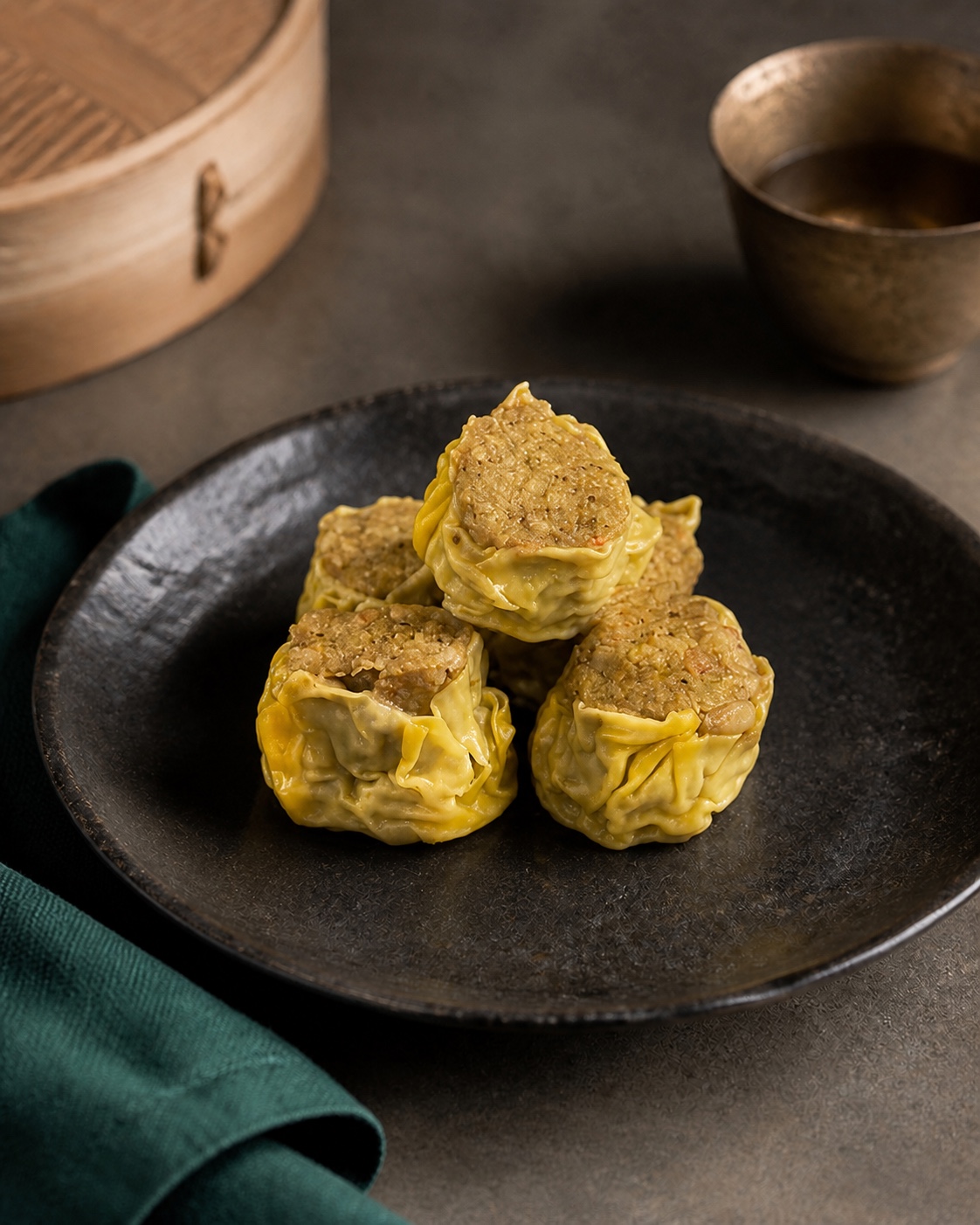 Styled serving of Nourvo Curry Seafood Siu Mai on a charcoal ceramic plate